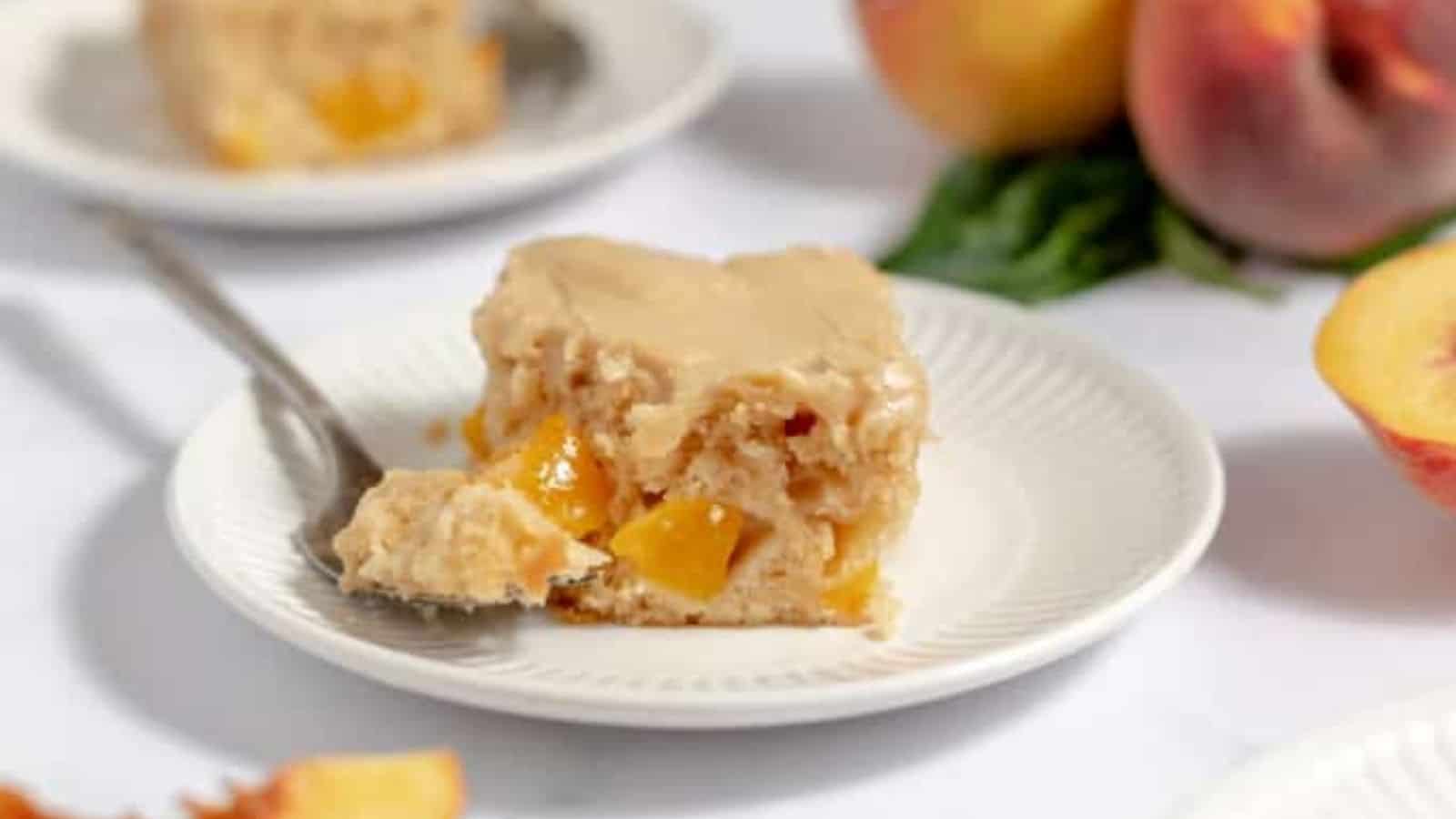 A slice of peach cake and a spoonfull of it on a plate.