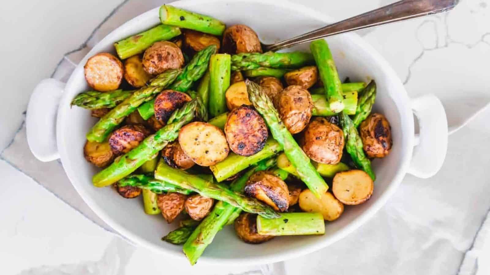 Top view of garlic parmesan roasted potatoes and asparagus with a spoon in a dish.