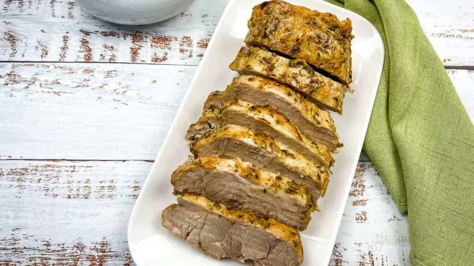 German Pork Loin on a platter with a gravy boat nearby.