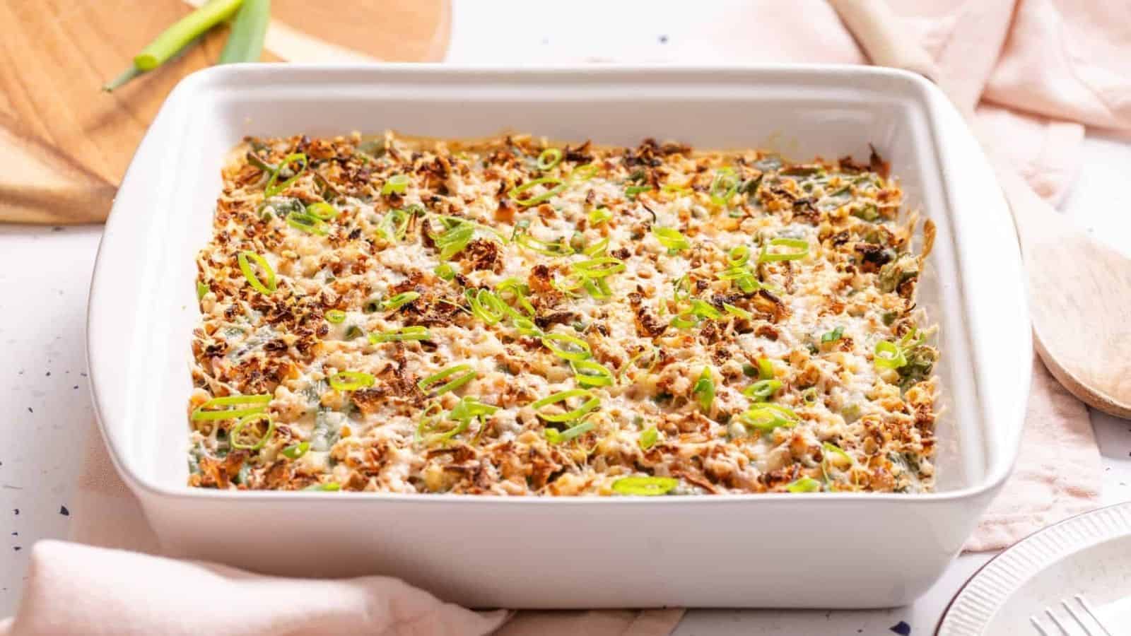 A  Green Bean Casserole with Cream Cheese topped with a golden-brown crust and garnished with sliced green onions.