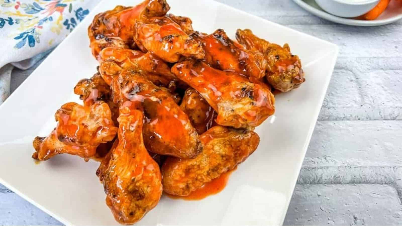 Close-up image of grilled wings with buffalo sauce on a plate.
