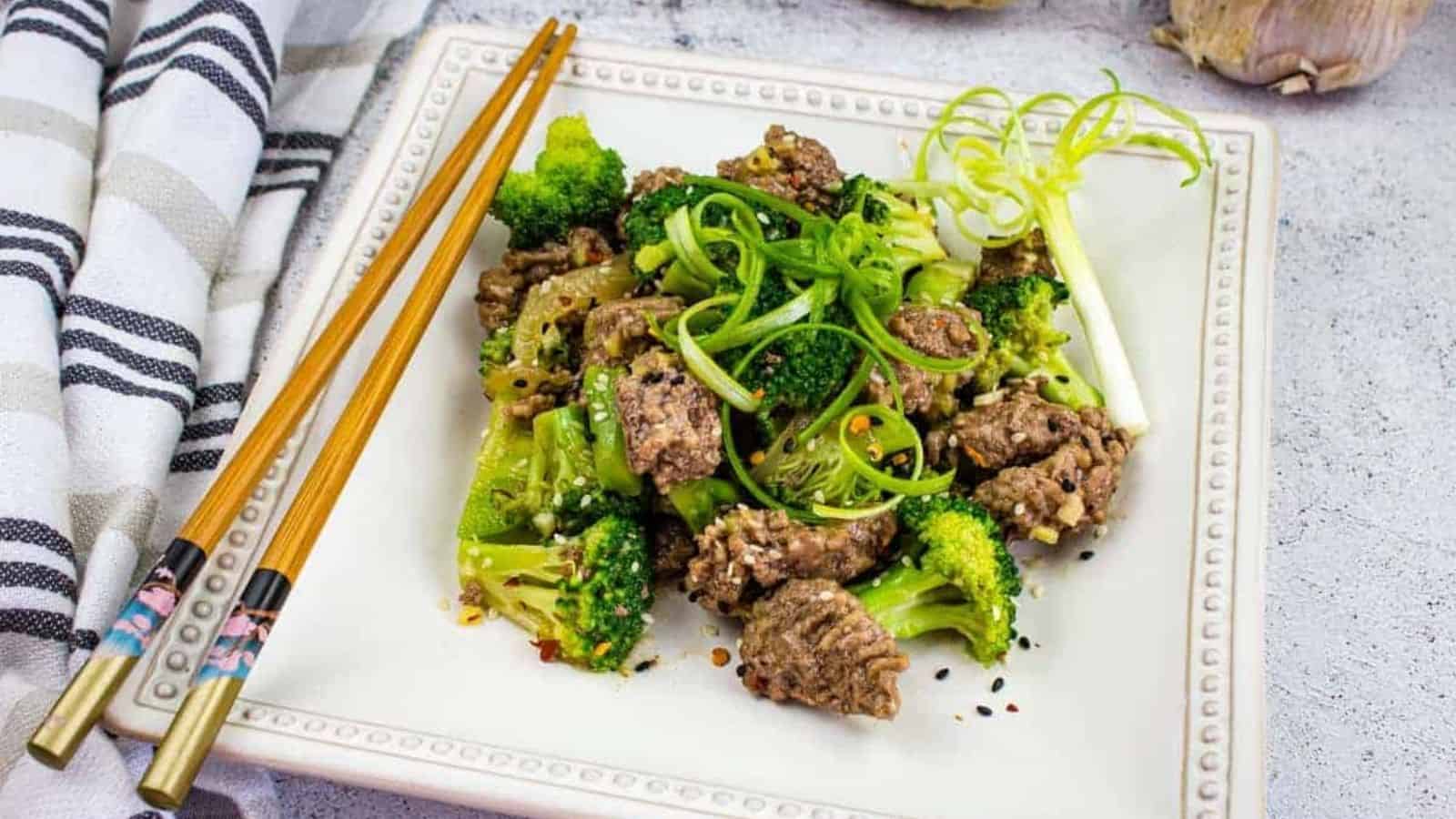 A plate of beef and broccoli with chopsticks.