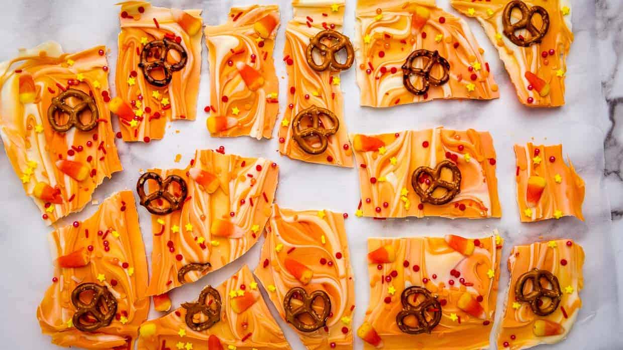 Orange pretzel bark with pretzels on a marble countertop.