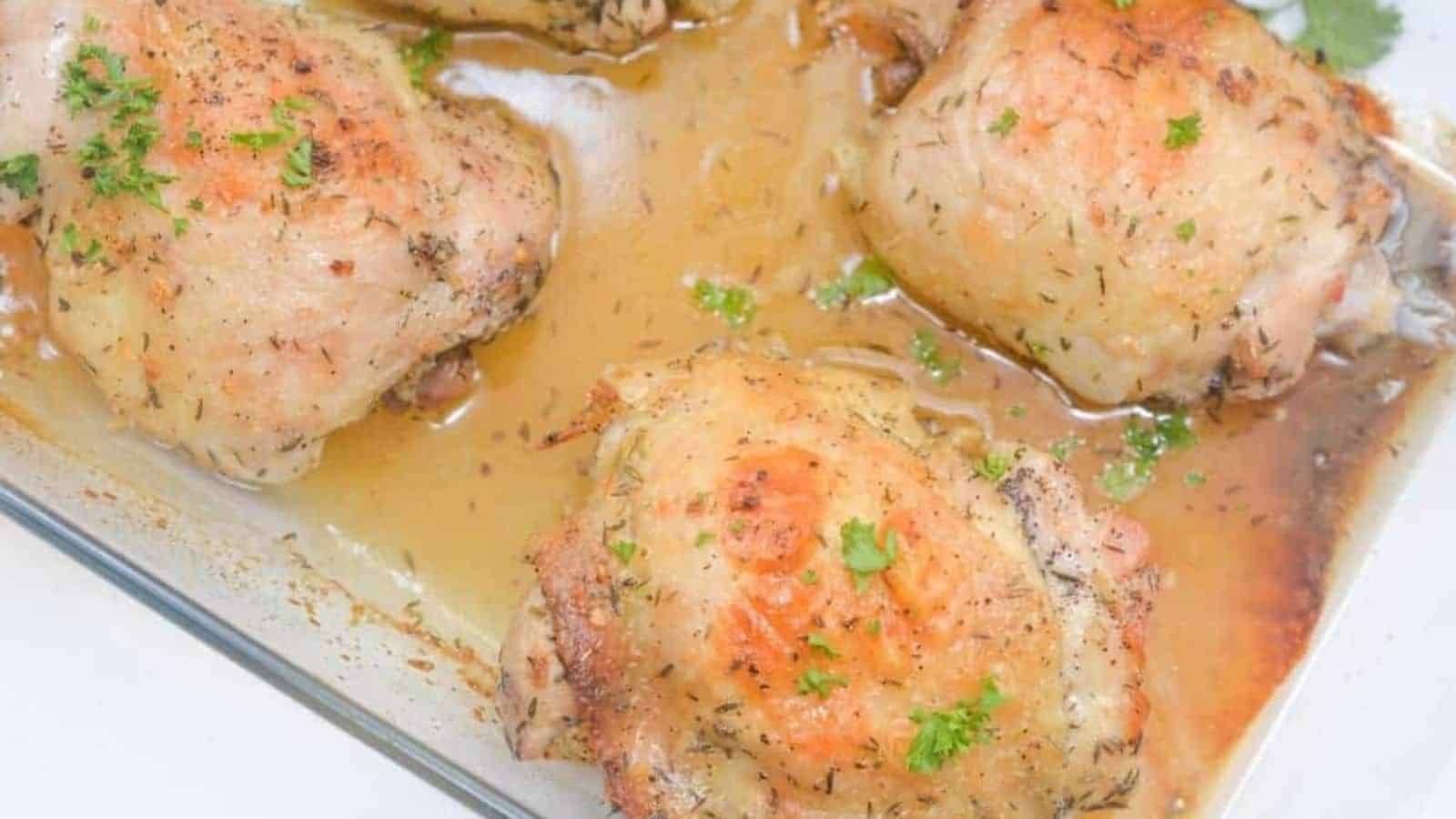 Honey and lemon baked chicken thighs with parsley on top in a baking dish.