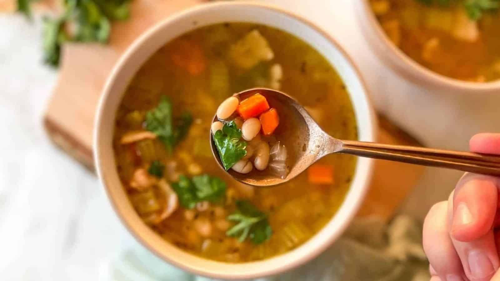 A spoonful of soup is shown in the foreground over a bowl of Instant Pot Navy Bean Soup.