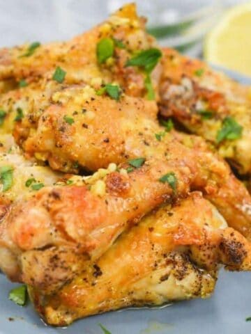 Chicken wings on a plate with lemon wedges.