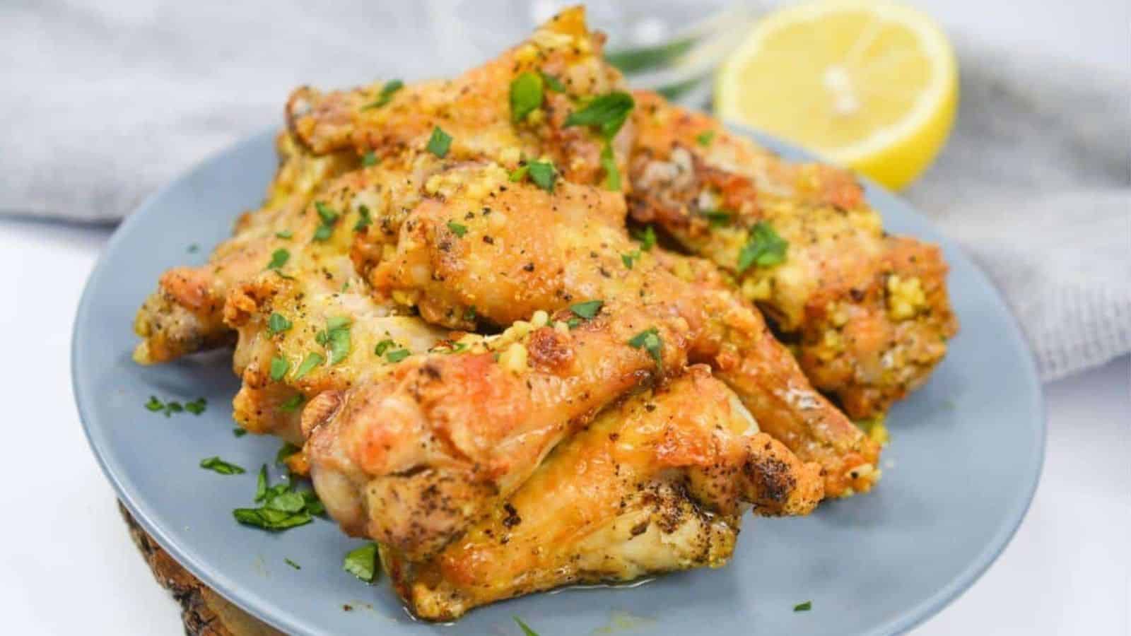 Chicken wings on a plate with lemon wedges.