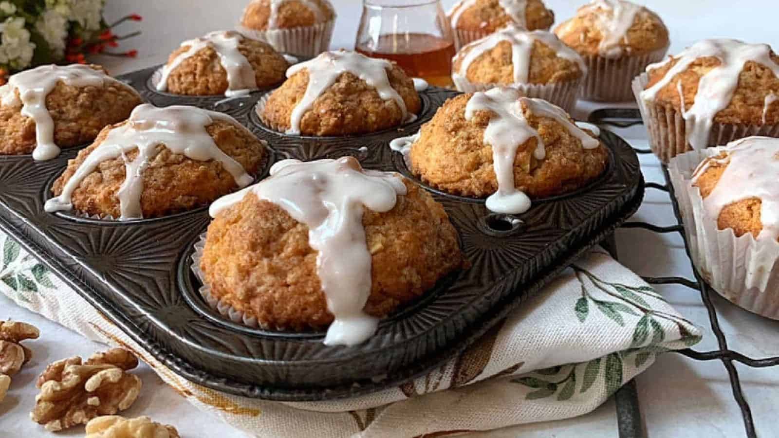 Muffins in a pan with icing and walnuts.