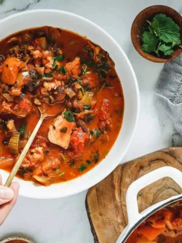 Someone scooping a spoon of Moqueca from a bowl.