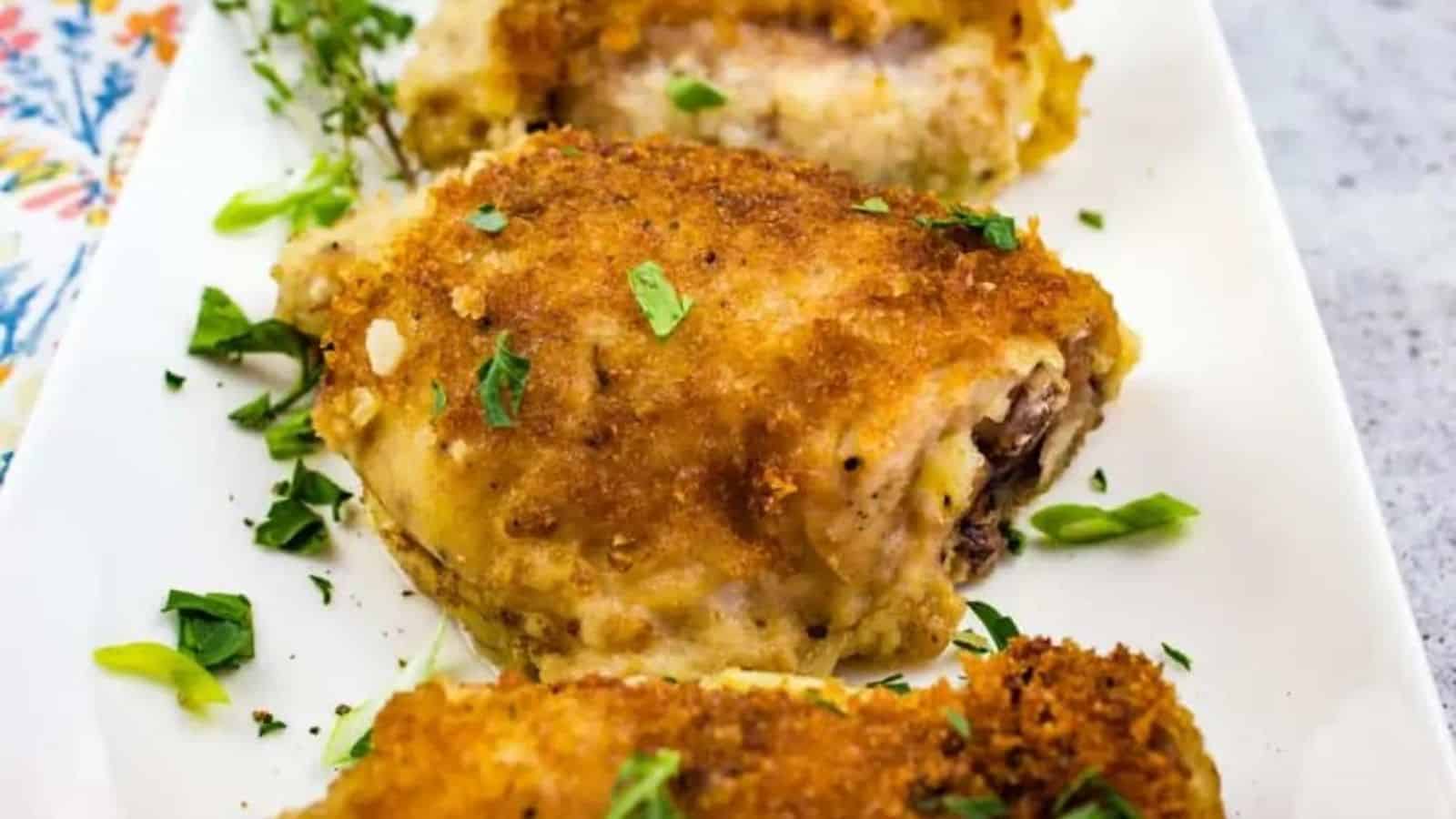 Close-up image of oven baked chicken with creamy onion gravy on a white plate.