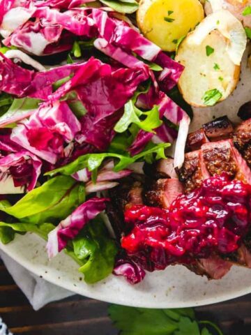 A plate of Pan Seared Duck Breast with Cranberry Maple Sauce.