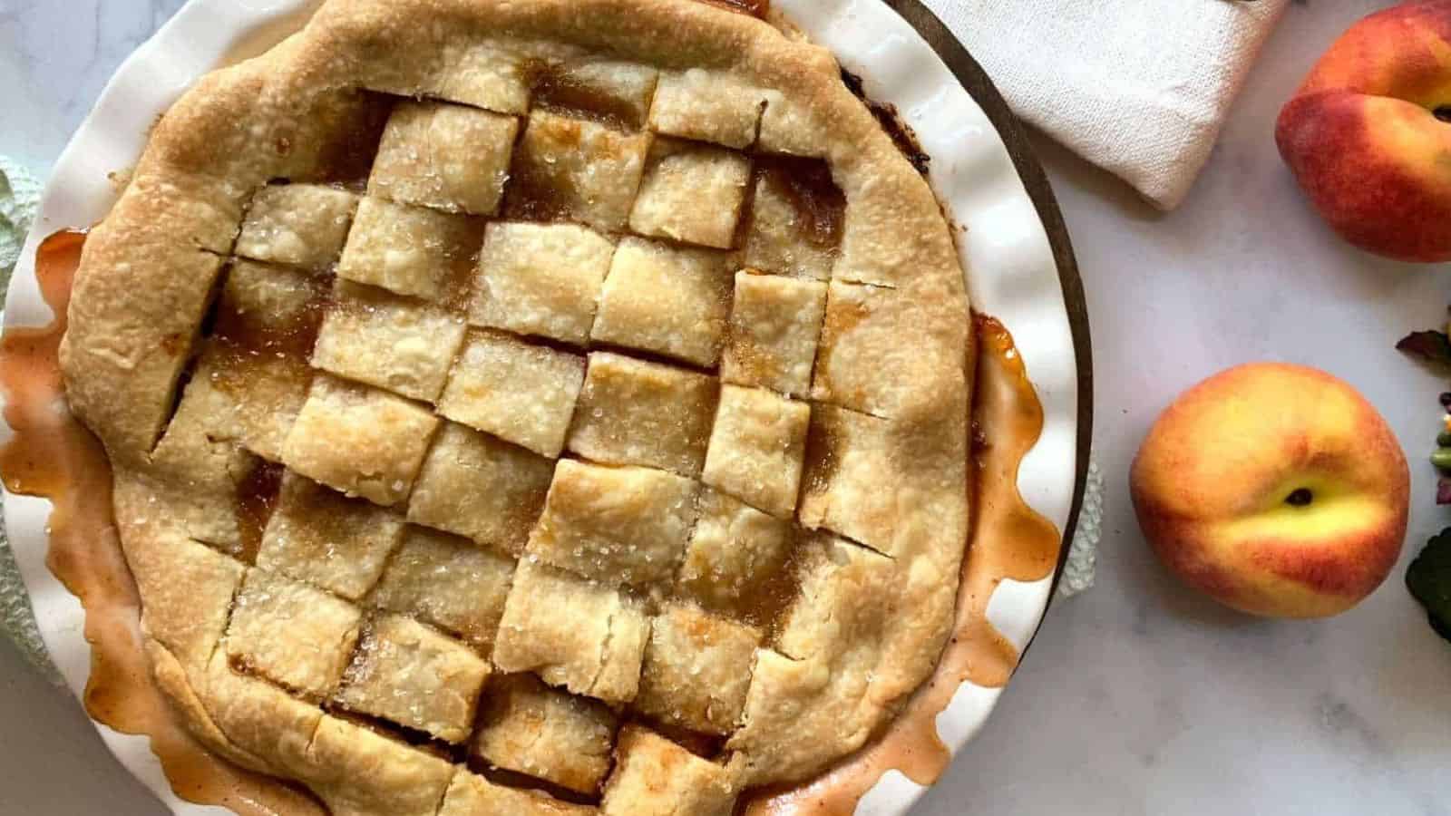Overhead shot of peach pandowdy with fresh peaches.