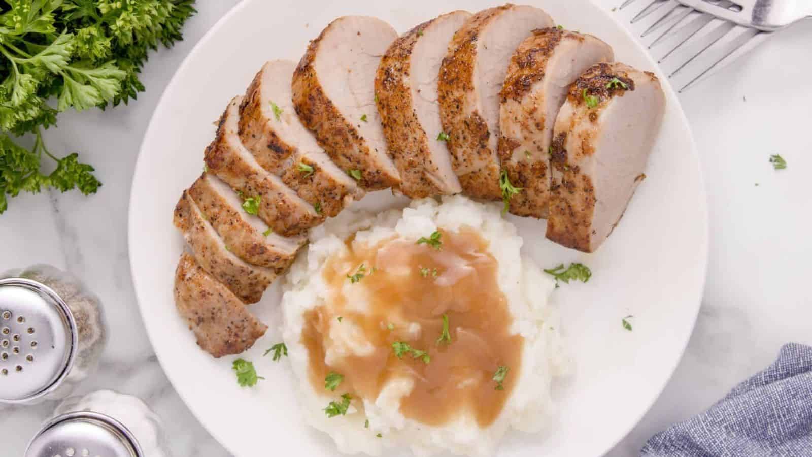 Pork Tenderloin on a white plate with some mashed potatoes.