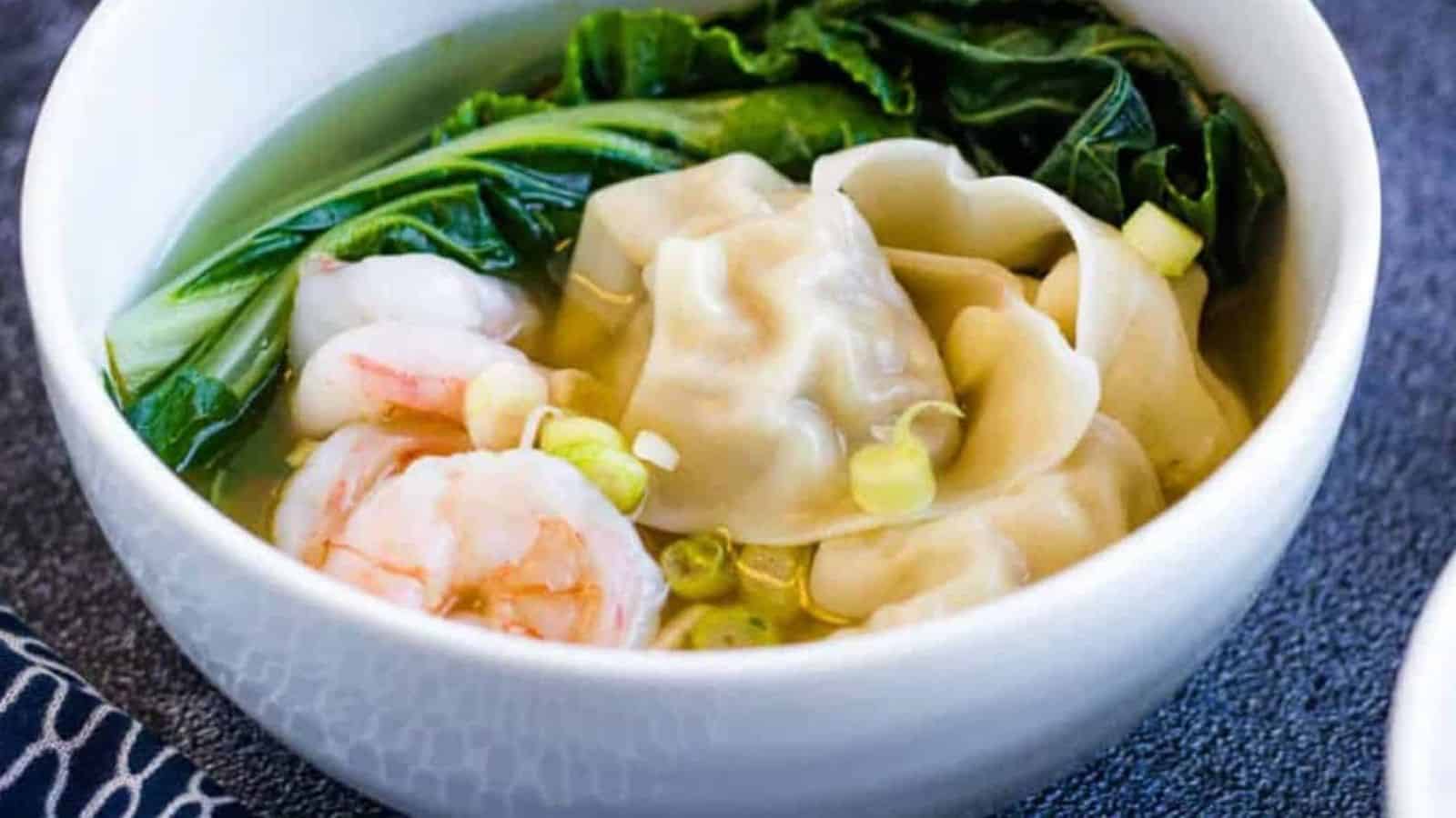 A bowl of wonton soup with shrimp in it.