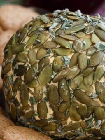 Close-up imageof pumpkin herb cheeseball with cookies and a knife.