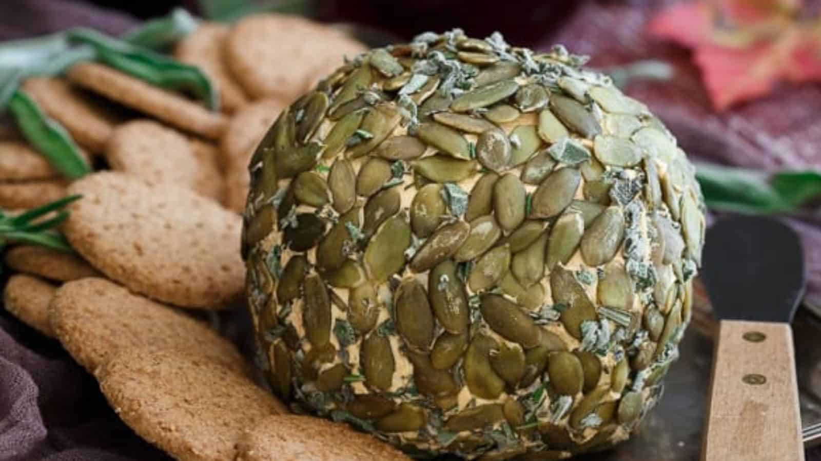 Close-up imageof pumpkin herb cheeseball with cookies and a knife.