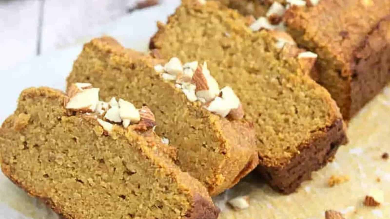 Healthy pumpkin bread in slices on a cutting board and around it with peanut butter on the side.