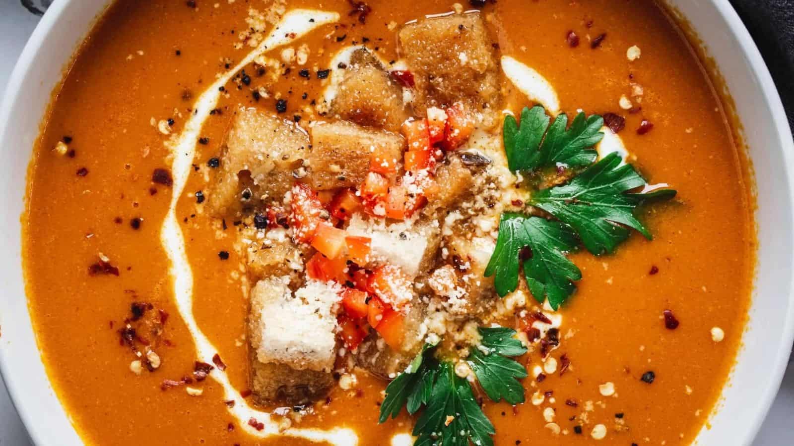 Close-up overhead image of red pepper bisque in a bowl.