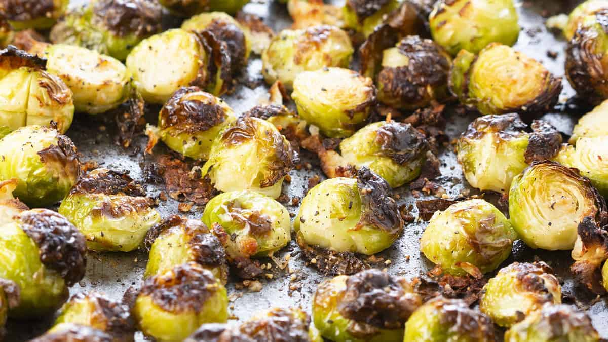 A close up image of crispy roasted Brussels Sprouts on a sheet pan.