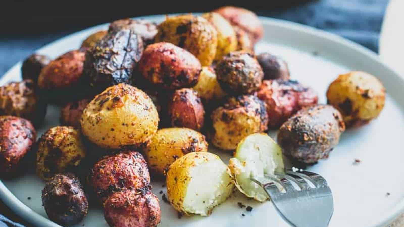 Close-up of roasted peri-peri potatoes on a plate with a fork in one of them.