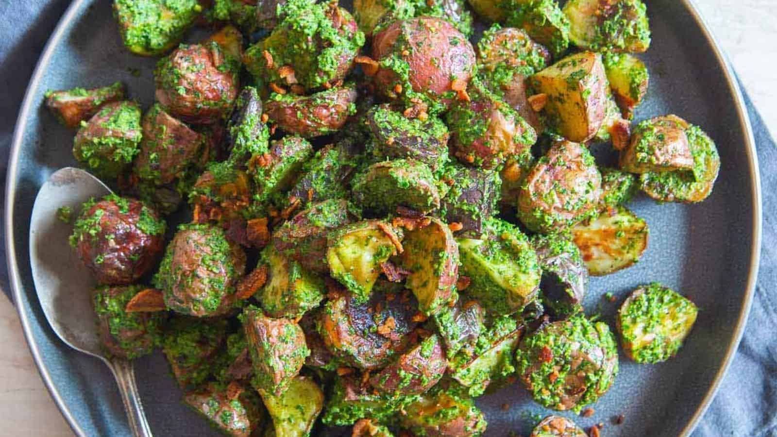 Overhead image of roasted pesto potatoes with a spoon on a blue plate.