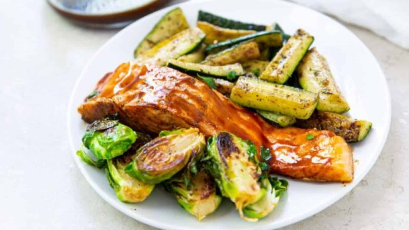 Salmon on blackstone griddle with veggies on a white plate.