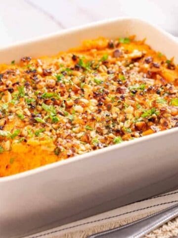 An angled shot of savory sweet potato casserole served in a baking dish.