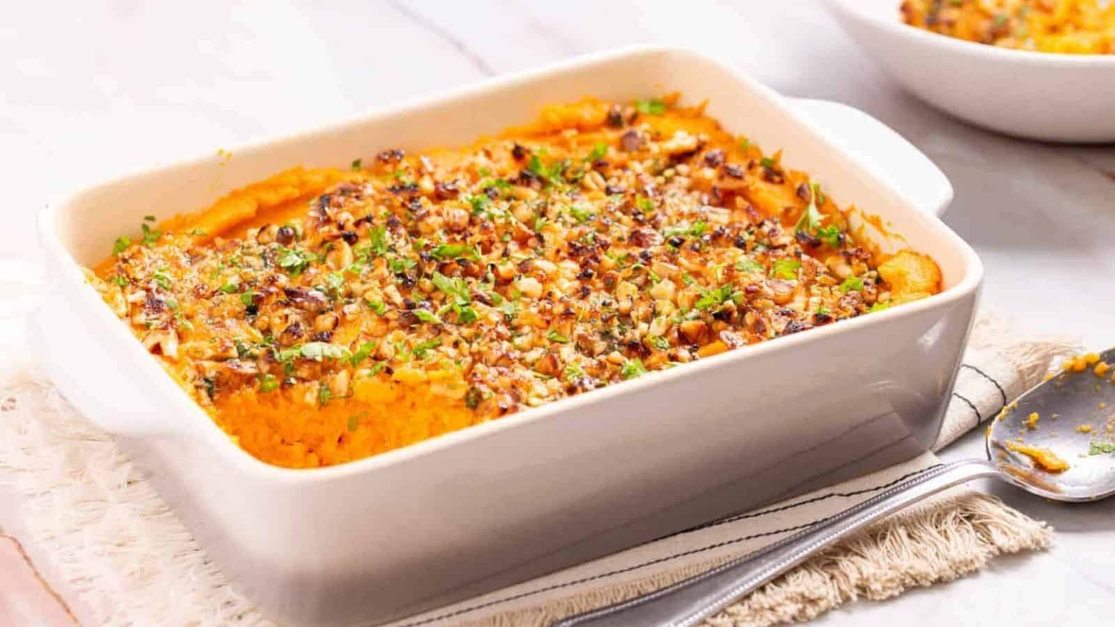 An angled shot of savory sweet potato casserole served in a baking dish.