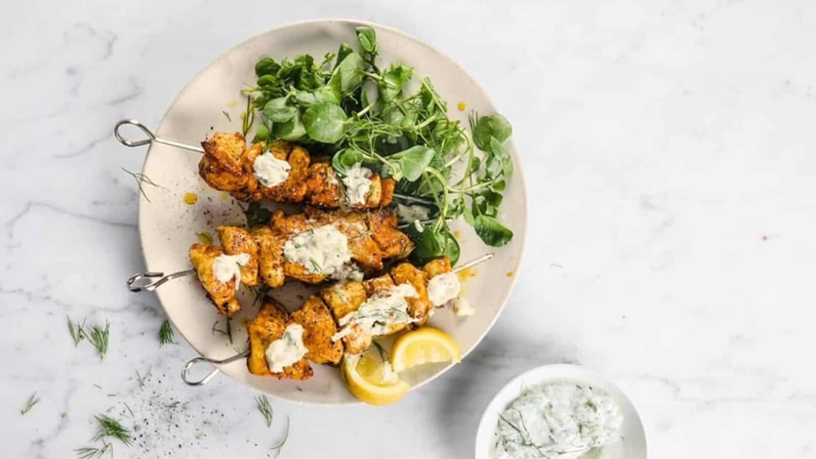 A plate of shawarma kebabs with greens and lemon slices.