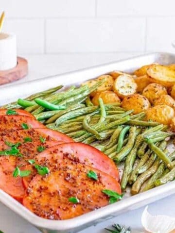 Sheet pan ham dinner with veggies on a tray.