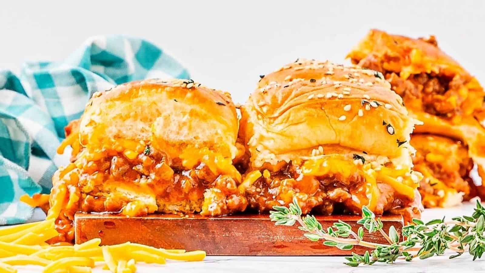 Close-up image of 2 sloppy joe sliders on a wooden board.