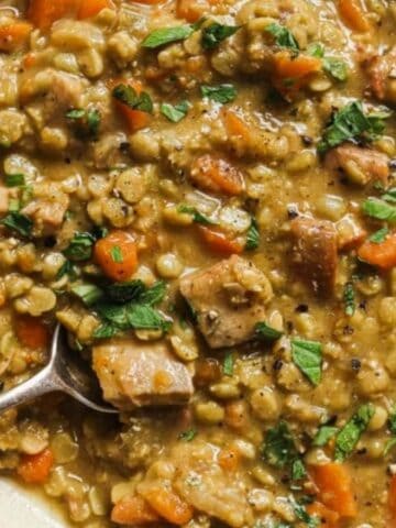 Top view of slow cooker split pea soup with a spoon on a plate.