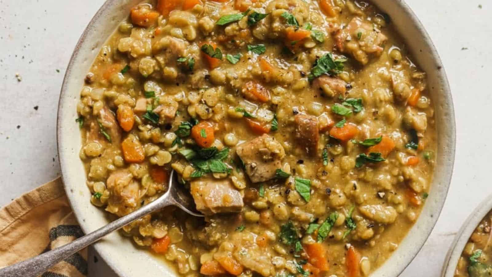 Top view of slow cooker split pea soup with a spoon on a plate.