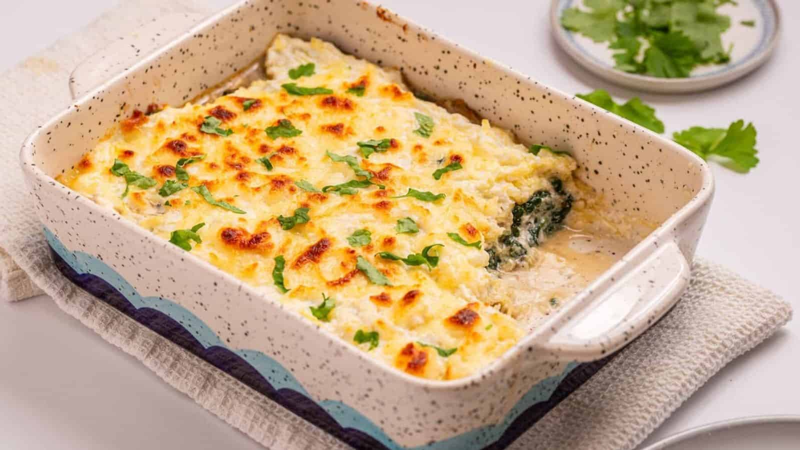 An image of spaghetti squash casserole with a serving missing from the lower right side of the baking dish.