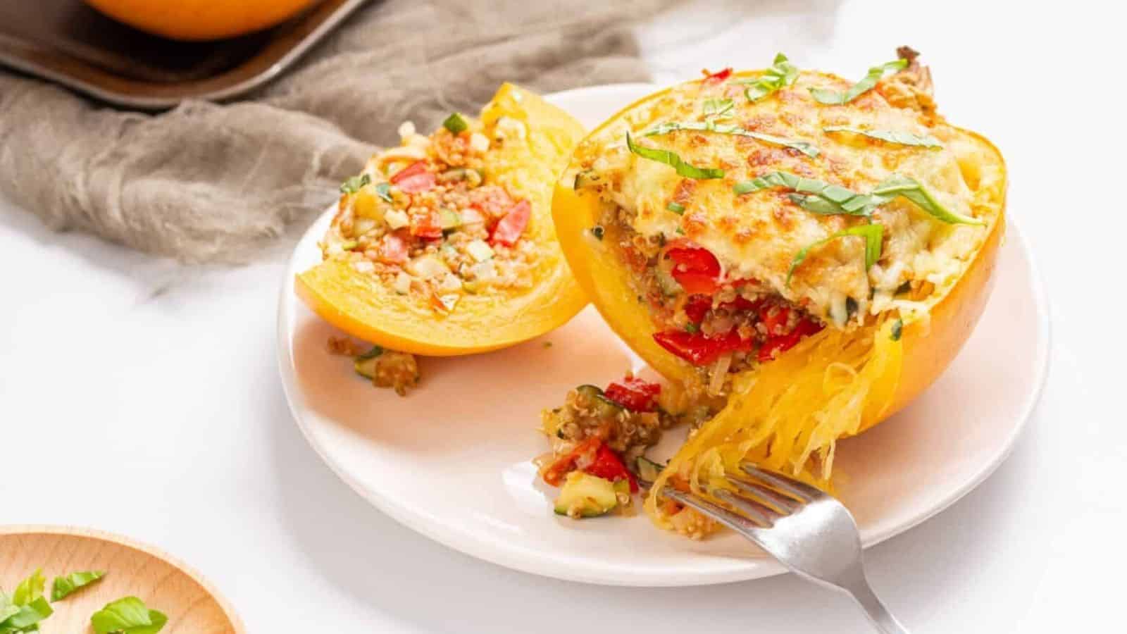 An image of two stuffed spaghetti squashes on a white plate with a fork slicing a part of one of the squashes.