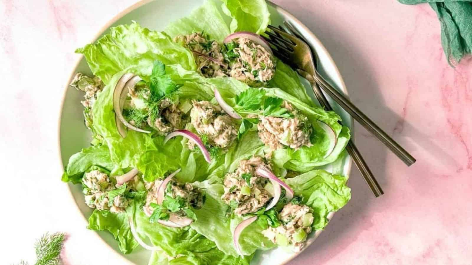 Healthy Tuna salad without mayo sits on a bed of iceberg lettuce surrounded by two forks, dill, and a green linen.