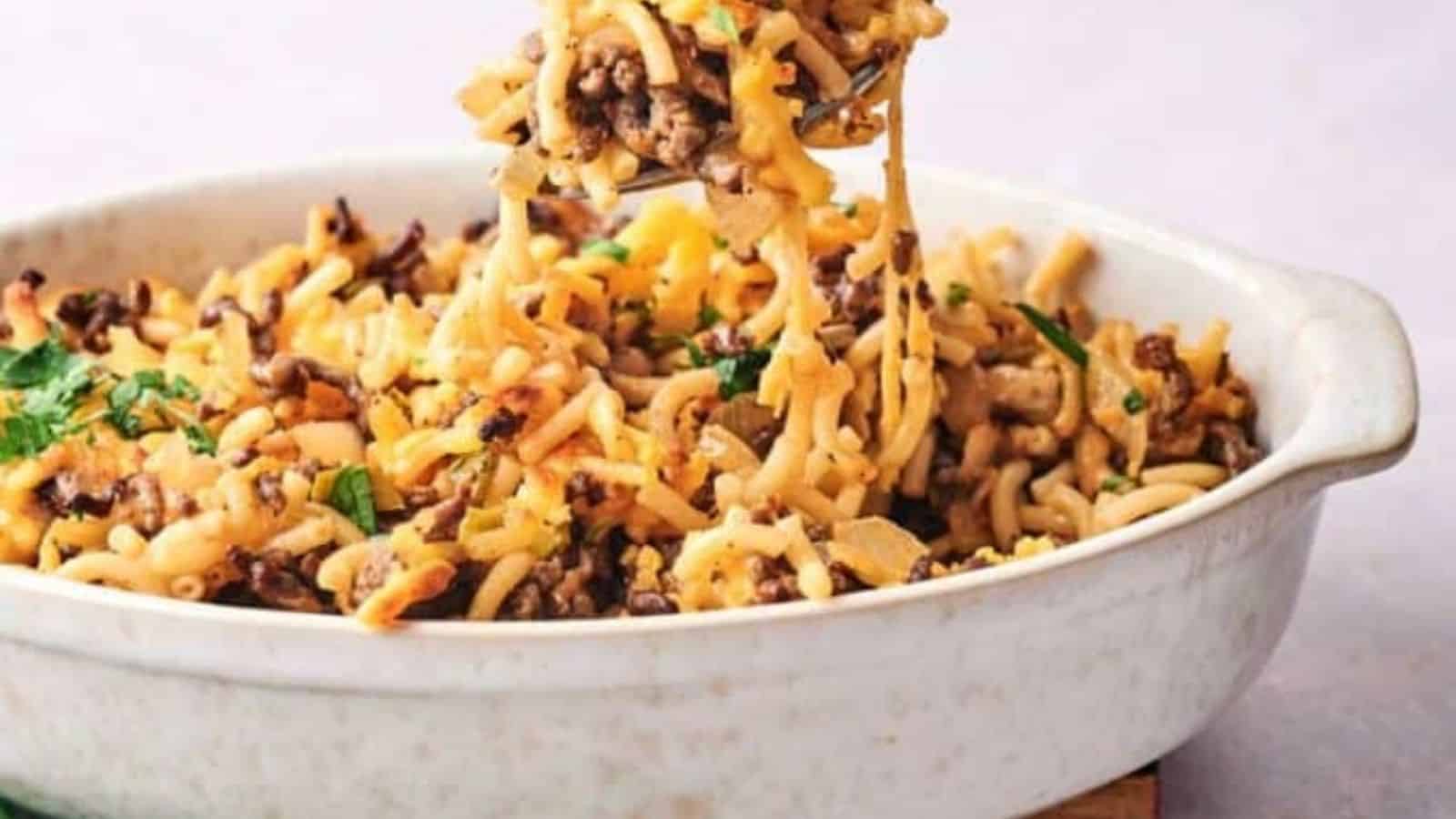 A spoonfull of air fryer cheeseburger casserole being lifted from the dish.