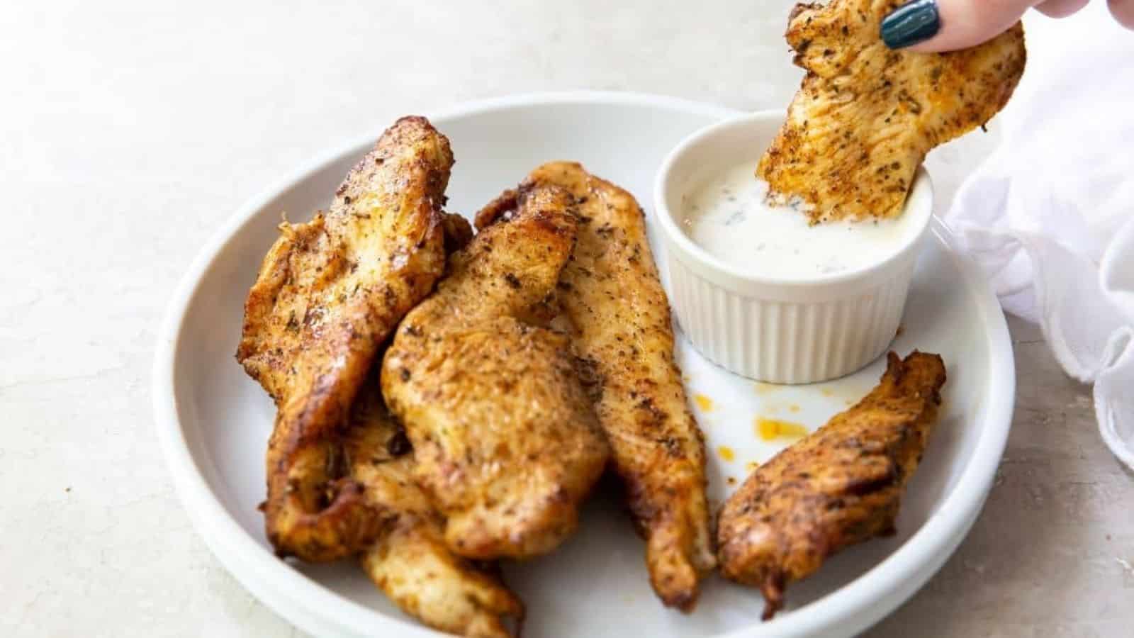 Air Fryer Chicken Breast Strips on a white plate with white sauce.