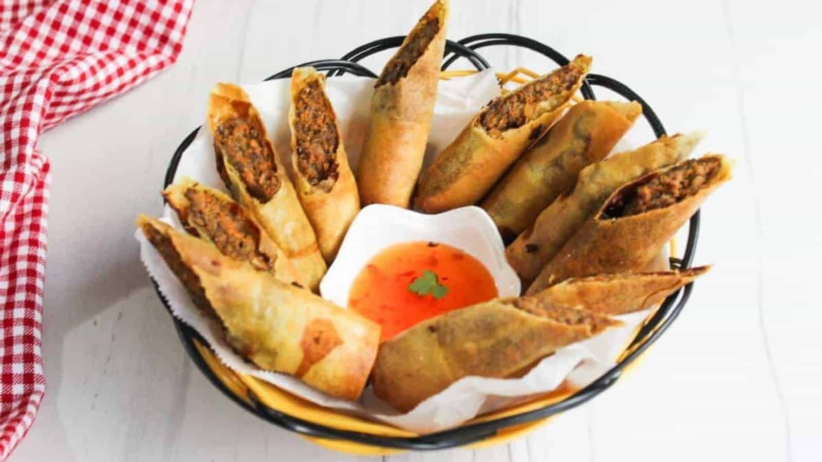 Filipino spring rolls in a basket with dipping sauce.