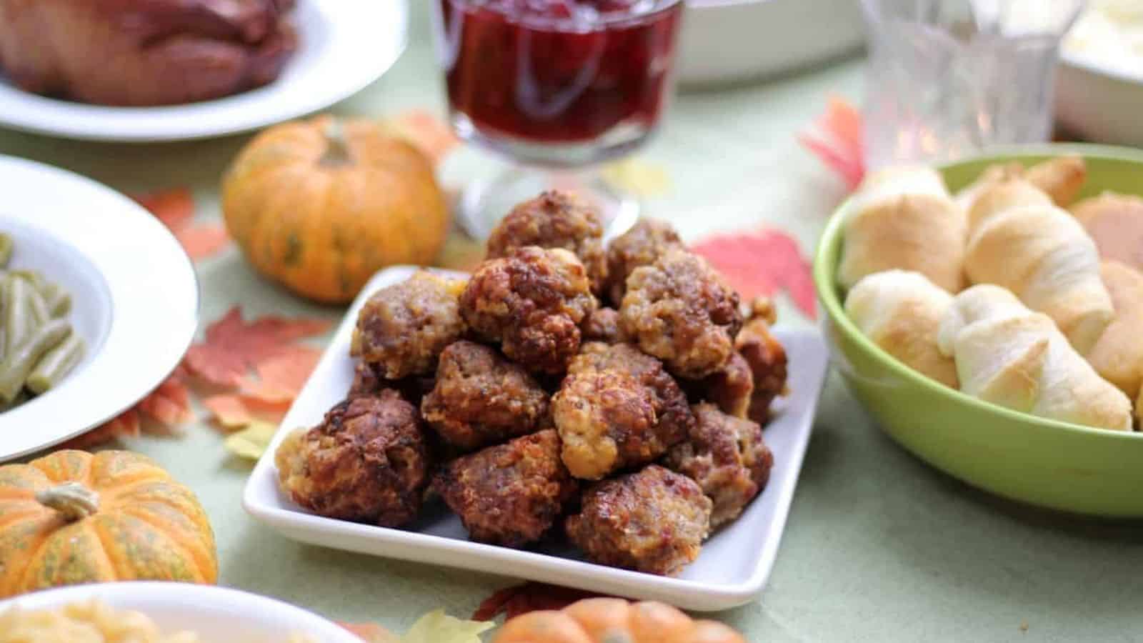 White plate of sausage balls on a Thanksgiving themed table.