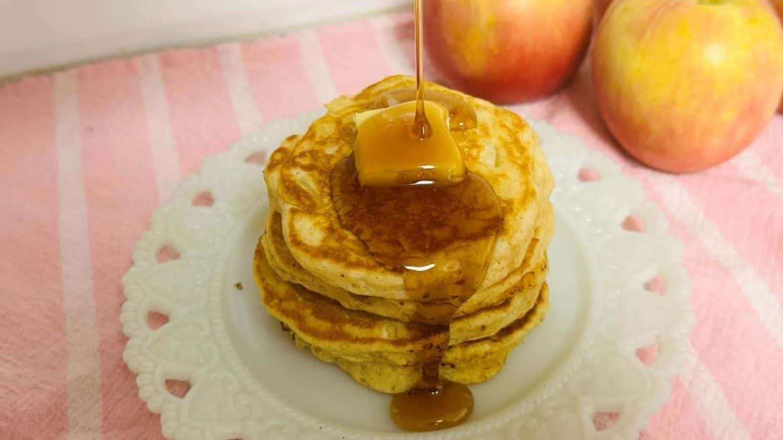 A stack of pancakes with syrup being poured over them.