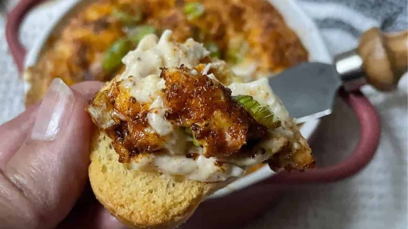 Crab dip in a dish on white towel with green onions and toasts.