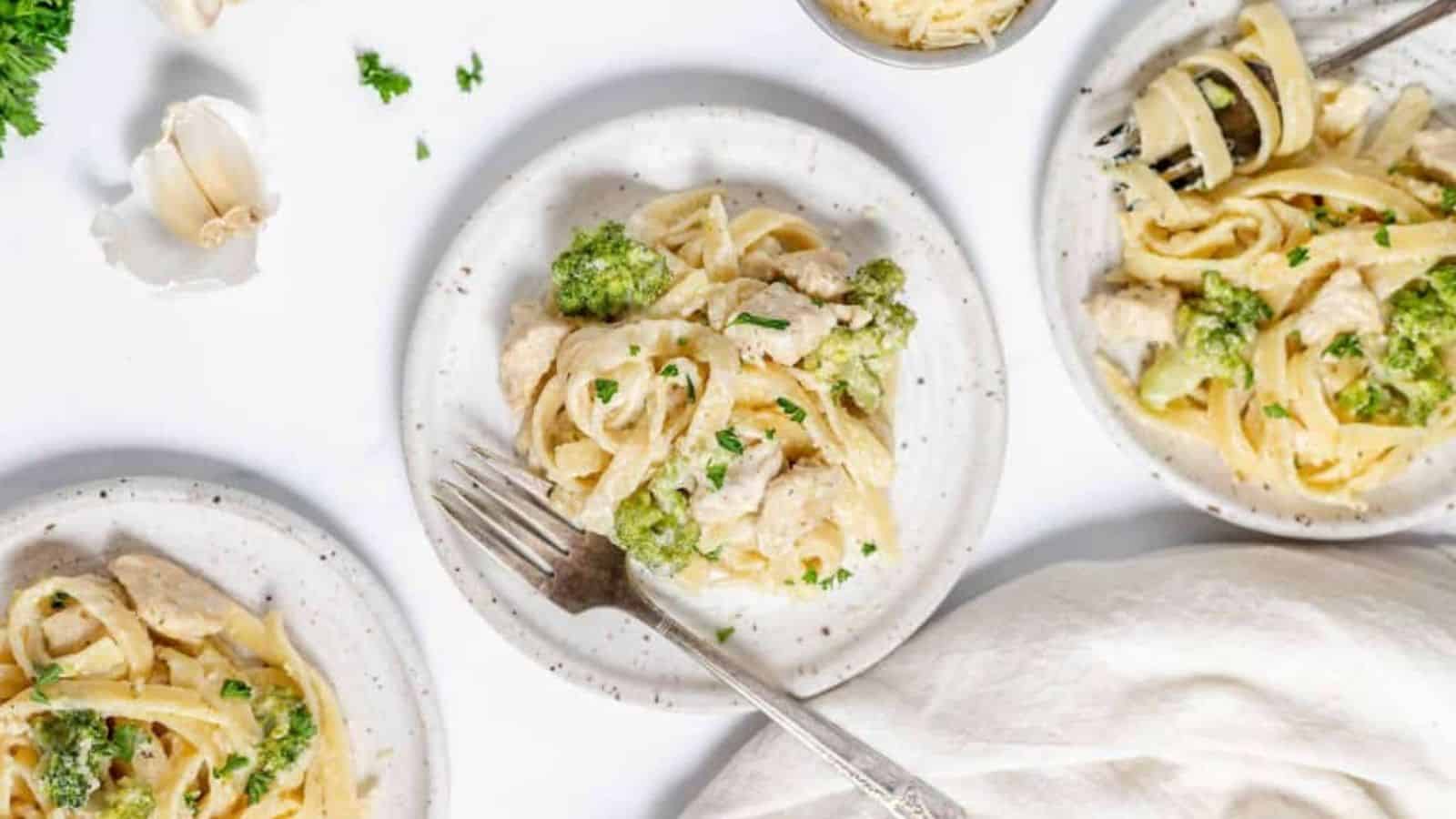 Overhead image of three plates of chicken broccoli alfredo.