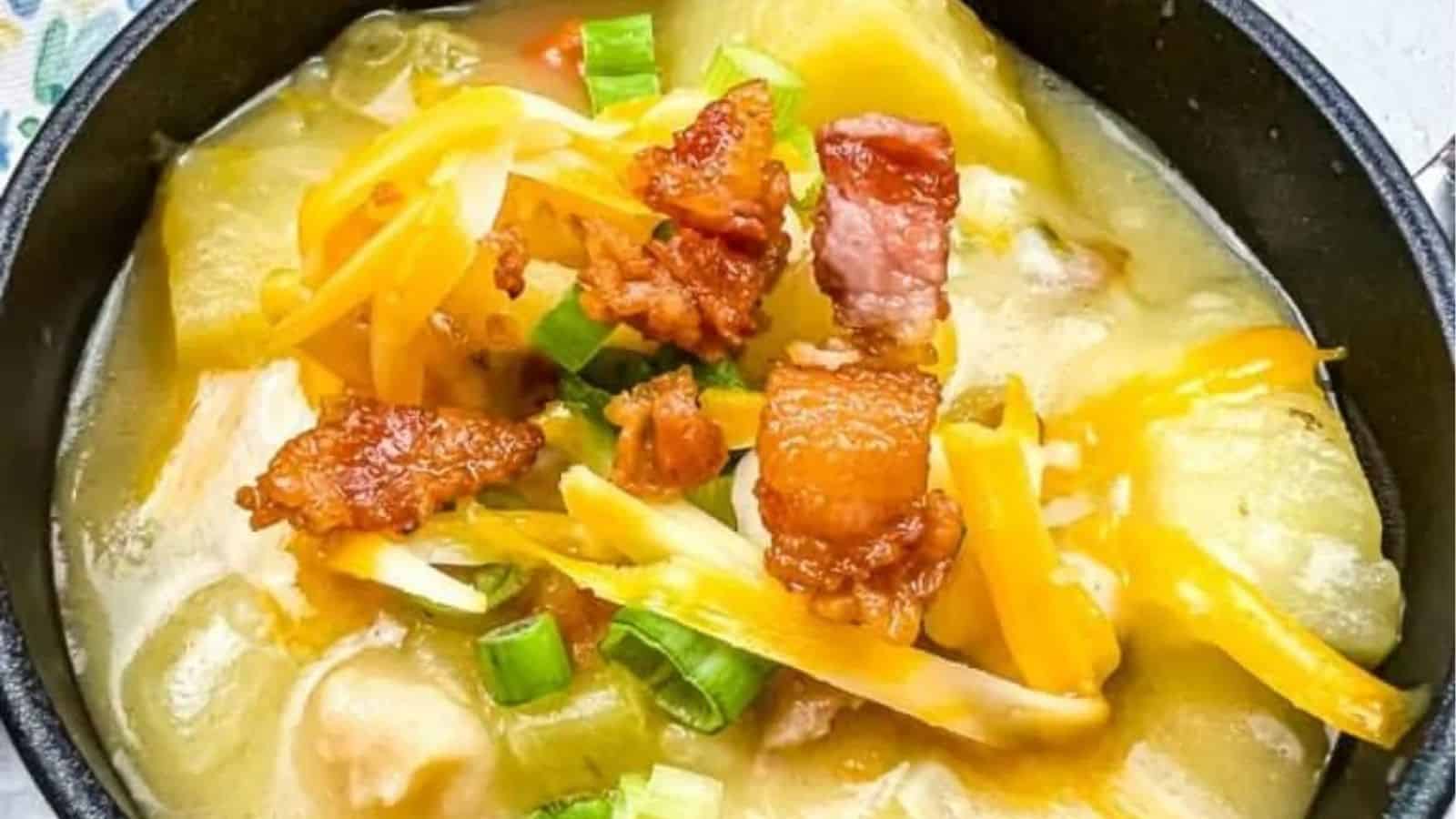 Close-up image fo fully loaded baked potato soup in a black pot.