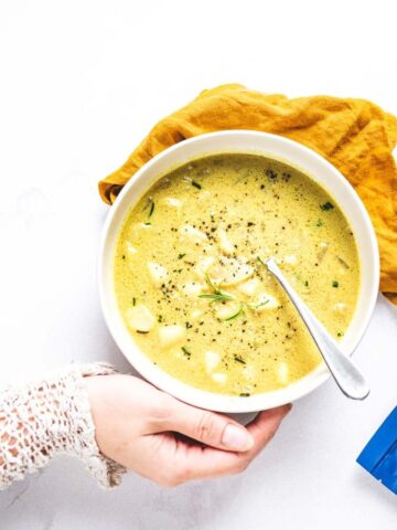 Someone holding a bowl of Golden Bliss Potato Soup.