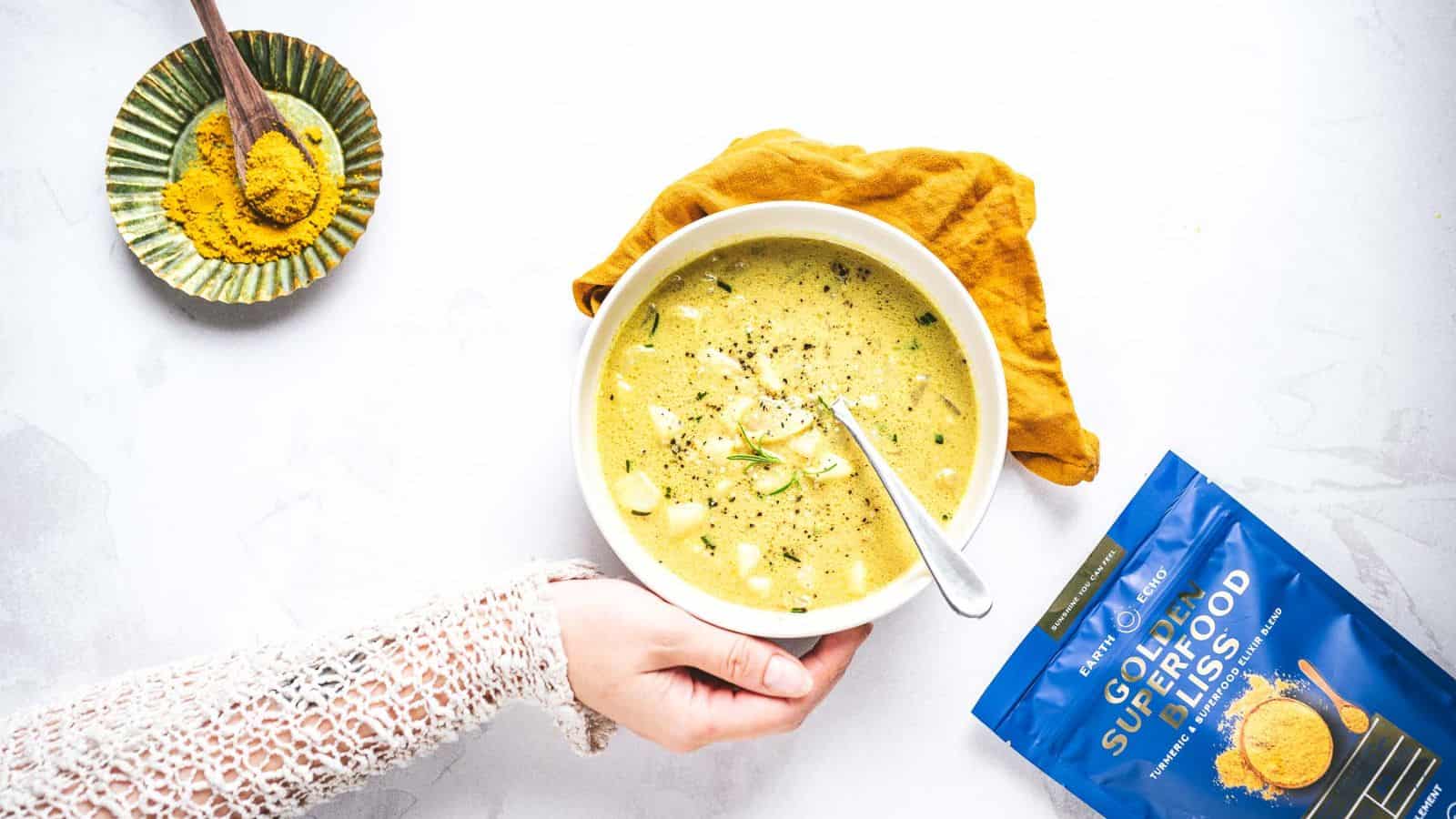 Someone holding a bowl of Golden Bliss Potato Soup.