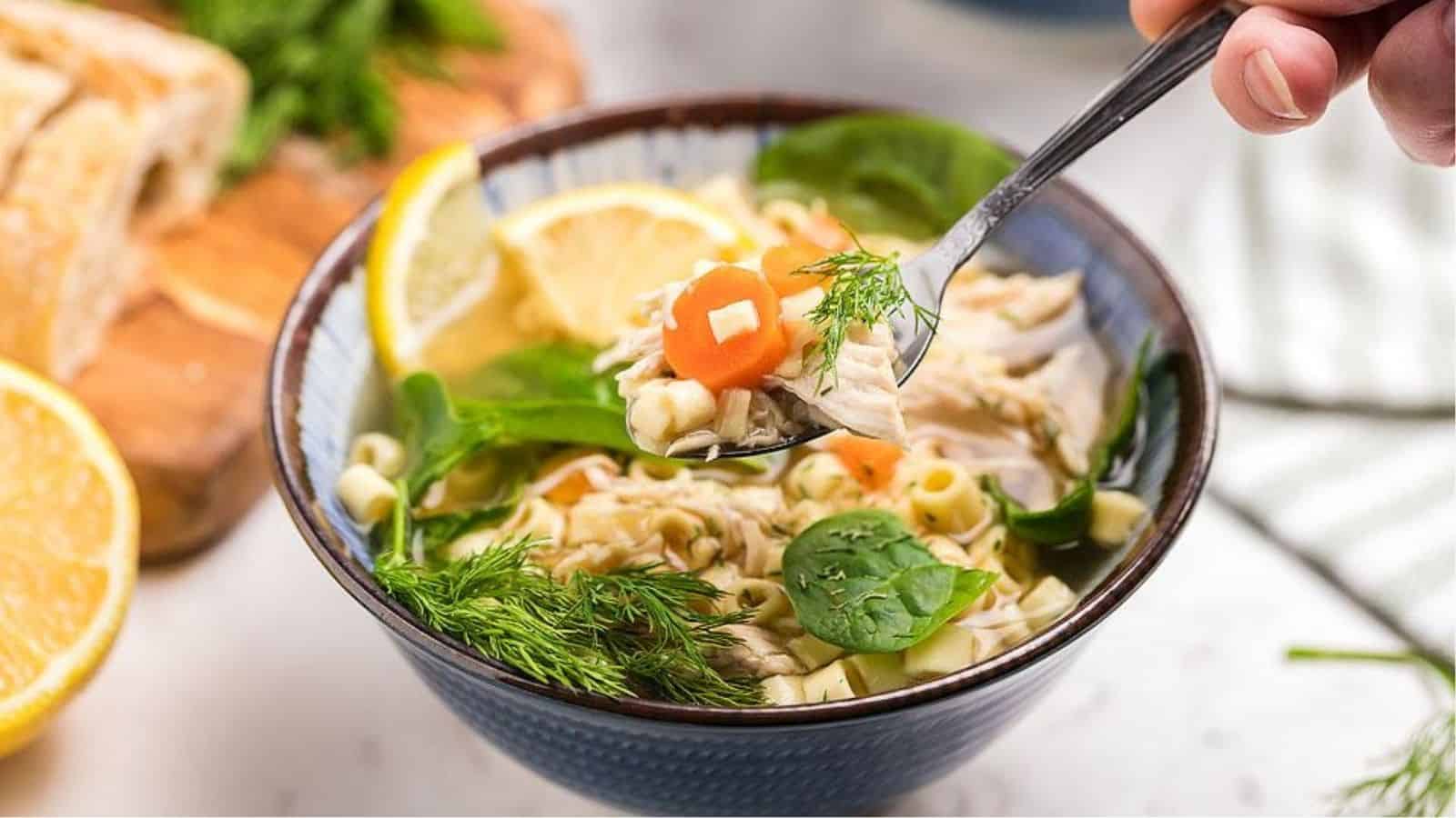 A spoonfull of greek avgolemono chicken soup being lifted from a bowl.