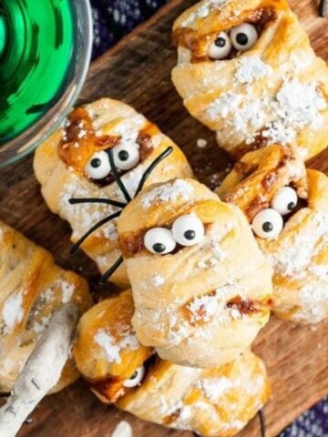 Overhead image of halloween snickers mummy treats on a wooden board.