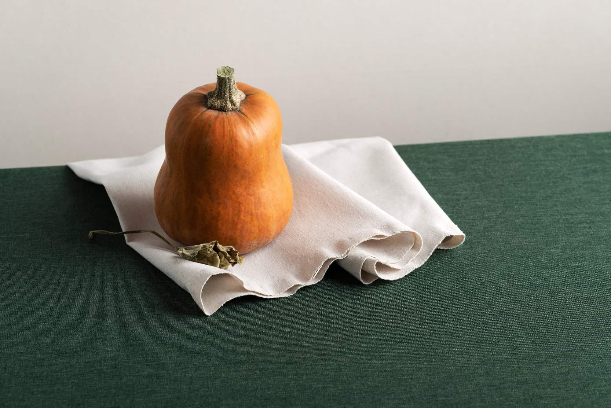 Honeynut Squash on a white cloth on a green table.