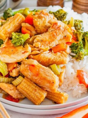 Hunan chicken with rice and chopsticks on a plate.